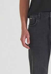 Vaqueros de denim gris oscuro con un corte slim, detalles sutiles de desgastado, diseño de cinco bolsillos y costuras en la cinturilla.