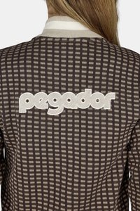 Hnedý károvaný sveter s kontrastnými svetlošedými akcentmi a bielym logom "pegador" vyšívaným na chrbte. Textúrovaná tkanina.