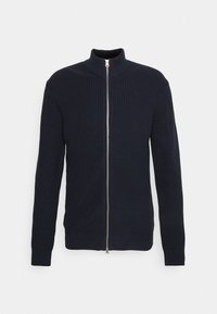 Námornícky pletený svetr s vysokým límcem, ribbovanou texturou a dlouhými rukávy. Má stříbrný zip a přiléhavý střih.