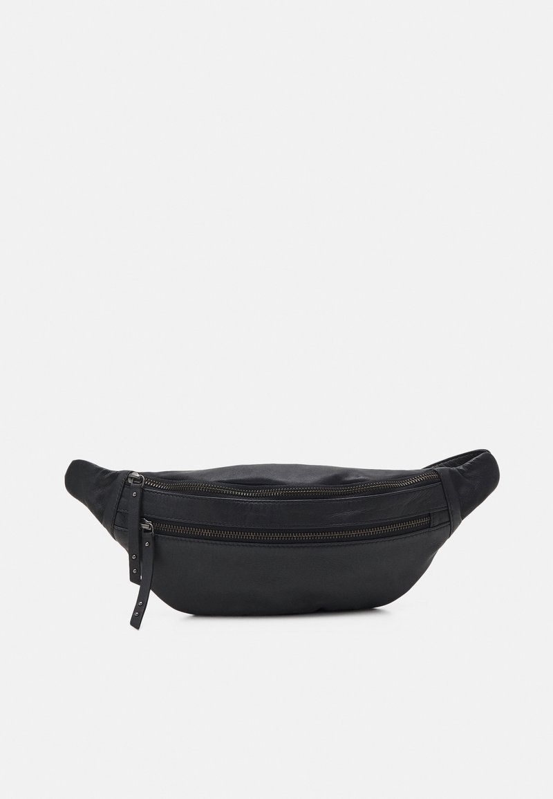 Sac banane en cuir noir avec deux compartiments zippés et des sangles réglables sur fond gris clair.