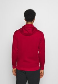 Rote Kapuzenjacke aus weichem Material, mit langen Ärmeln, gerippten Bündchen und Saum sowie einem lässigen Schnitt. Schlichte Ausführung ohne Muster.