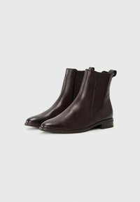 Bottines en cuir marron avec des pointes arrondies, des panneaux latéraux élastiques et des languettes de tirage. Texture lisse et talons bas empilés pour le confort.