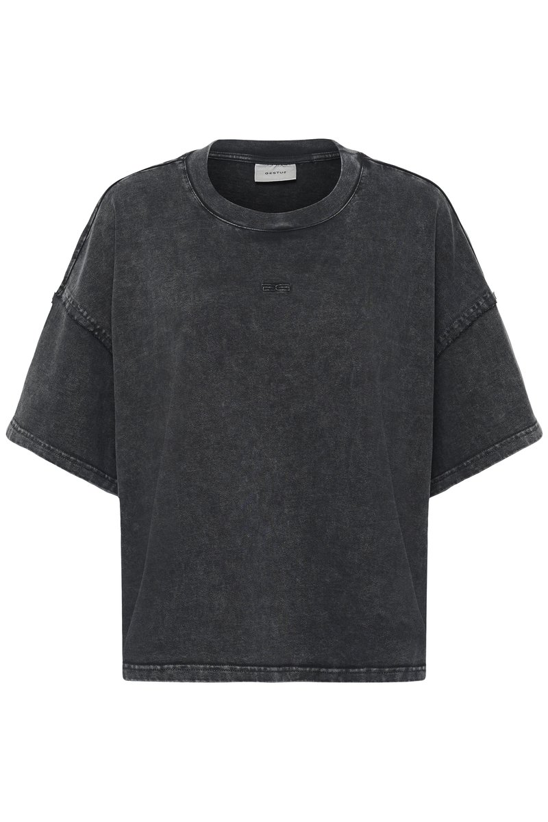 Kortærmet oversized t-shirt i falmet sort denim. Den har en rund hals, rå kanter og subtile logo-detaljer på forsiden.