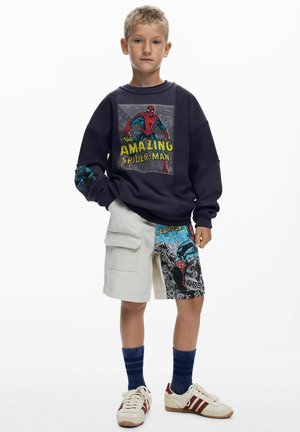 Marineblauwe sweatshirt met "Amazing Spider-Man" afbeelding, gecombineerd met beige cargoshorts met stripstijl patronen; witte en bordeauxrode sneakers.