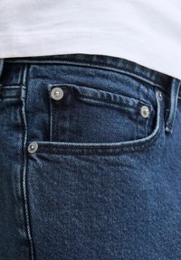 Ciemnoniebieskie dżinsy z teksturowanej tkaniny denim, pięciokieszeniowy fason i akcenty z metalowych detali w kolorze srebrnym.