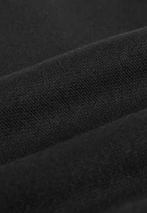Close-up of black fabric with visible knit texture and soft folds creating gentle curves and shadows.
