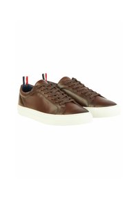 Bruine leren sneakers met een witte rubberen zool, voorzien van een ronde neus, vetersluiting aan de voorkant, en contrasterende rode en blauwe accenten op de hiel.