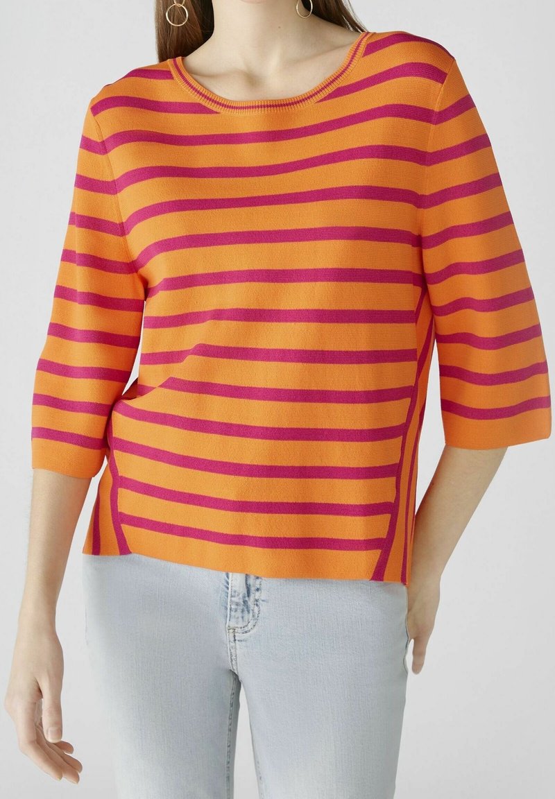 Pull rayé en orange et magenta, fabriqué en tissu doux. Doté d'un col rond et de manches trois-quarts, avec une coupe décontractée.