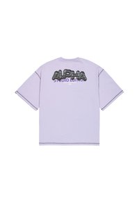 Tricou oversized mov cu un grafic mare din text negru "ALPHA" și "STUDIO EDITION" dedesubt, cu cusături contrastante pe margini.