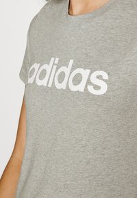 Šedé bavlnené tričko s bielym logom "adidas". Dizajn s okrúhlym výstrihom, krátkymi rukávmi a hladkou textúrou.