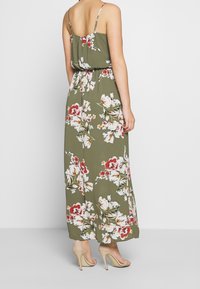 Maxi-mekko oliivinvihreänä, jossa on valkoisia ja punaisia kukkakuvioita. Ominaisuuksia ovat ohuet spagettiolkaimet ja rento malli, jossa on kerätty vyötärö.