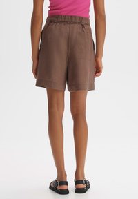 Shorts en lin marron avec taille élastique et poche arrière ; conçus pour le confort et la liberté de mouvement. Ourlet plat, coupe droite.