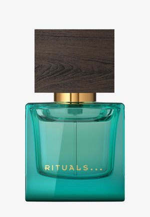 Vierkante turquoise glazen parfumfles met grote donkerhouten dop en gouden tekst "RITUALS" aan de voorkant.