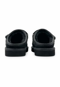 Zwarte instappers met een zachte binnenkant, voorzien van een gestructureerd buitenmateriaal en een lage rubberen zool. Het design aan de achterkant heeft afgeronde randen.