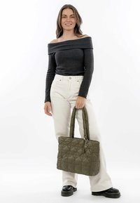 Sac fourre-tout matelassé vert olive avec doubles poignées, de forme rectangulaire, avec un motif en losanges cousus et un charm décoratif.