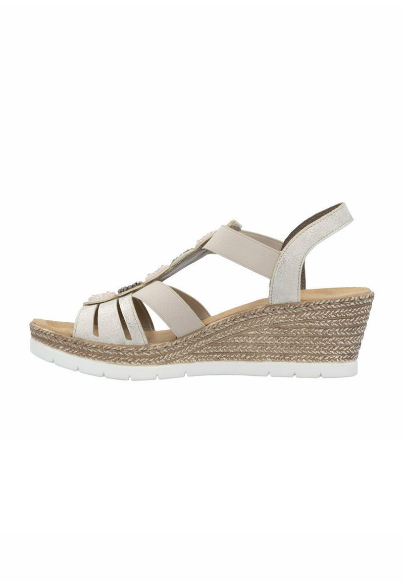 Sandały na koturnie w jasnym beżu z elastycznymi paskami i plecionką z juty. Posiadają zaokrąglony obcas i wyściełaną wkładkę.