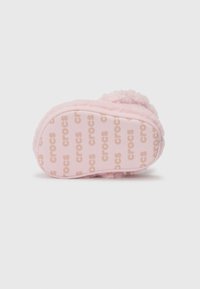 Vaaleanpunaiset pörröiset tossut, joissa on pehmeä rakenne, pyöreä muoto ja kumipohja, jossa on "crocs"-logo. Suunnittelu on yksinkertainen ja sileä.