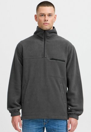 Gray fleece pullover with a high collar, half-zip front, chest pocket with zipper, and side pockets; features elastic cuffs and hem.