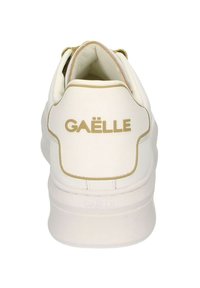 Sneaker bianco con accenti dorati e logo. Parte superiore in pelle liscia e colletto imbottito. Suola bianca resistente con dettagli sottili del marchio.