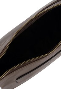 Brązowa sk�órzana torba z zapięciem na zamek. Wnętrze jest czarne, o gładkiej teksturze. Złote okucia zamka zdobią górną krawędź.
