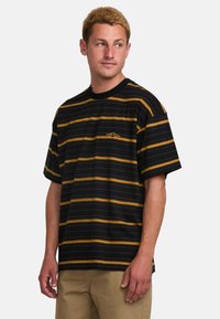 Camiseta de manga corta a rayas negras y doradas con cuello redondo y detalle de logo, confeccionada en suave tejido de mezcla de algodón.