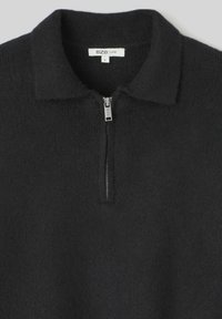 Pull-over noir à quart de zip en tissu doux et texturé. Comprend un col avec col et une fermeture éclair argentée avec une étiquette minimale à l'intérieur. Taille L.