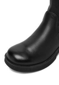 Botină din piele neagră până la gleznă, cu vârf rotund, textură netedă și talpă din cauciuc cu nervuri. Fără accesorii sau modele vizibile.