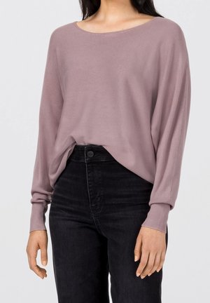 Pullover à manches longues, ample, en tricot mauve doux avec un large col rond et des poignets côtelés, porté sur un jean noir taille haute.