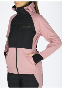 Roze en zwarte capuchonjack met een rits aan de voorkant, puffy zwarte panels en elastische manchetten met duimopeningen. Gouden logo op de borst.
