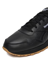 Mustast nahast toss, millel on struktureeritud pealmine osa, ümar nina ja mustad paelad. Omaduseks kummist kummist tald ja peen bränding küljel.