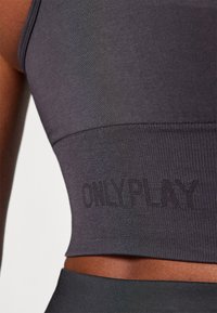 Pelēks sportisks topiņš ar ribota tekstūra. Iezīmēts ar izšūtu "ONLYPLAY" logotipu apakšmalā. Forma pieguļoša ar gludu apdari.