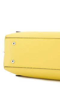Gelbe Lederhandtasche mit strukturierter Oberfläche, die silberne Nieten am Boden und kontrastierende Nähte entlang der Kanten aufweist.