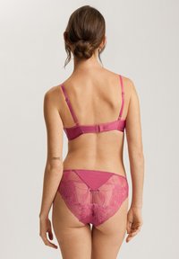 Set di lingerie magenta composto da un reggiseno liscio con spalline regolabili e slip in pizzo con motivi floreali e tessuto semi-trasparente sul retro.