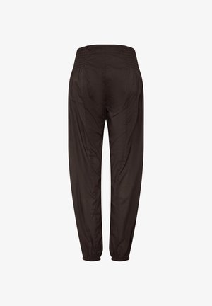 Pantalones cónicos color marrón oscuro con cinturilla y puños elásticos, confeccionados con tela lisa, vistos desde atrás.