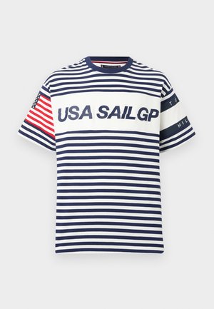 Navyblauw-wit gestreept shirt met korte mouwen, met de tekst "USA SAIL GP", Amerikaanse vlag op de linker mouw, en "Tommy Hilfiger" banden op de rechter mouw.
