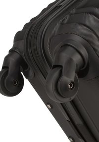 Schwarzer Hartschalenkoffer im Detail, mit strukturiertem Finish, zwei schwenkbaren Rädern und einem Reißverschluss entlang der Kante für sicheren Verschluss.