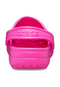 Des Crocs rose vif avec une surface texturée, une sangle de talon réglable et une tige perforée pour la ventilation. Légers et fabriqués en matériau synthétique.