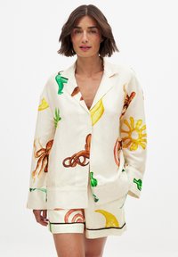 Linne pyjamaset med en krämfärgad bas och livfulla tryck av frukter och havsdjur; jackan har krage och framfickor, shorts med kontrasterande bård.