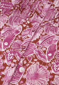 Kurzärmlige, knöpfbare Bluse aus einem reichhaltigen braunen Stoff mit pinken Blumen- und abstrakten Mustern, ausgestattet mit einem gerafften Krägen und passenden Knöpfen.