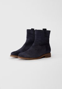Bottines en suède bleu marine avec un bout arrondi, fermeture éclair sur le côté et un petit talon empilé. Texture lisse et design minimaliste.