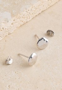 Silver stud earrings with a smooth, rounded shape and polished finish. Includes a butterfly clasp for secure wear.
