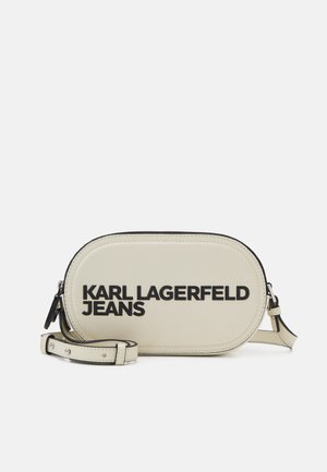 Sac à bandoulière ovale de couleur crème en matériau lisse, avec le texte audacieux "KARL LAGERFELD JEANS" en noir et une bandoulière amovible.