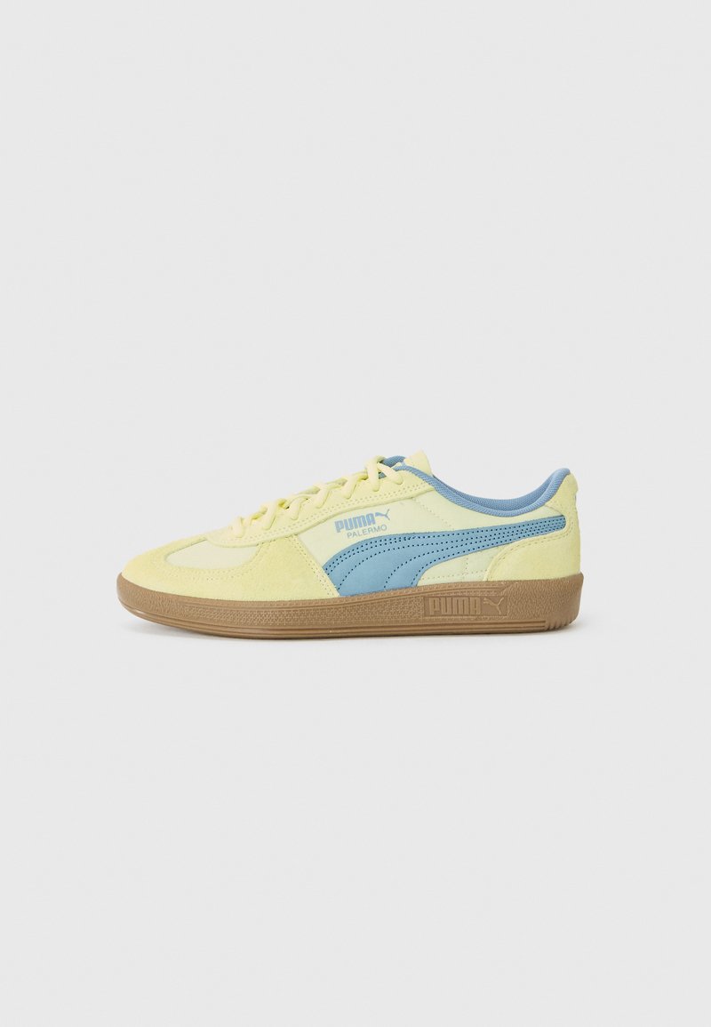 Des baskets Puma avec un dessus en daim jaune et bleu, une semelle en caoutchouc, un système de laçage traditionnel et un logo sportif sur le côté.