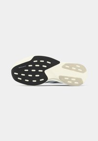 Suela de zapato con una base de goma negra y acentos blancos, patrón de agarre texturizado y agujeros recortados para flexibilidad y tracción.