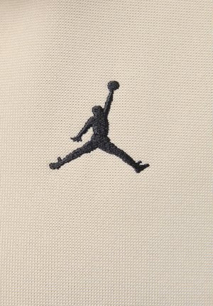 Black embroidered Jumpman logo on textured beige fabric, depicting a figure in a dynamic pose holding a basketball.