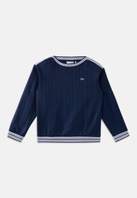 Chemise bleu marine à manches longues avec texture côtelée, col, poignets et ourlet rayés blancs, avec un petit logo crocodile vert sur la poitrine.