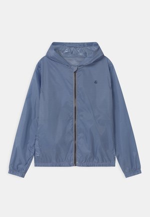 Veste légère à rayures bleues avec fermeture éclair et capuche, poignets élastiques et un petit logo sur la poitrine gauche. Texture lisse et design décontracté.