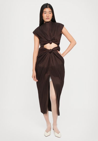 Robe plissée marron avec un col montant, une section médiane découpée et un détail noué à la taille. Texture lisse et fente jusqu'à la cuisse.