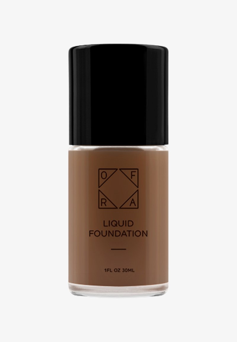 Brun flydende foundation i en klar glasflaske med et sort låg. Har et minimalistisk etiketdesign og måler 1 FL OZ (30 mL).