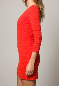 Červené, přiléhavé šaty s dlouhými rukávy, s texturovanými svislými rýhy po celém povrchu. Výstřih do V a délka ke kolenům. Hladká, elastická tkanina.